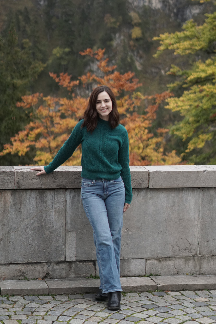 Dria standing by a stone wall in autumn